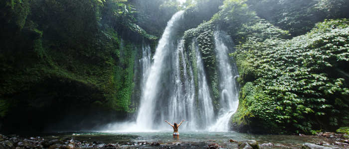 Girl underneath Bali waterfall